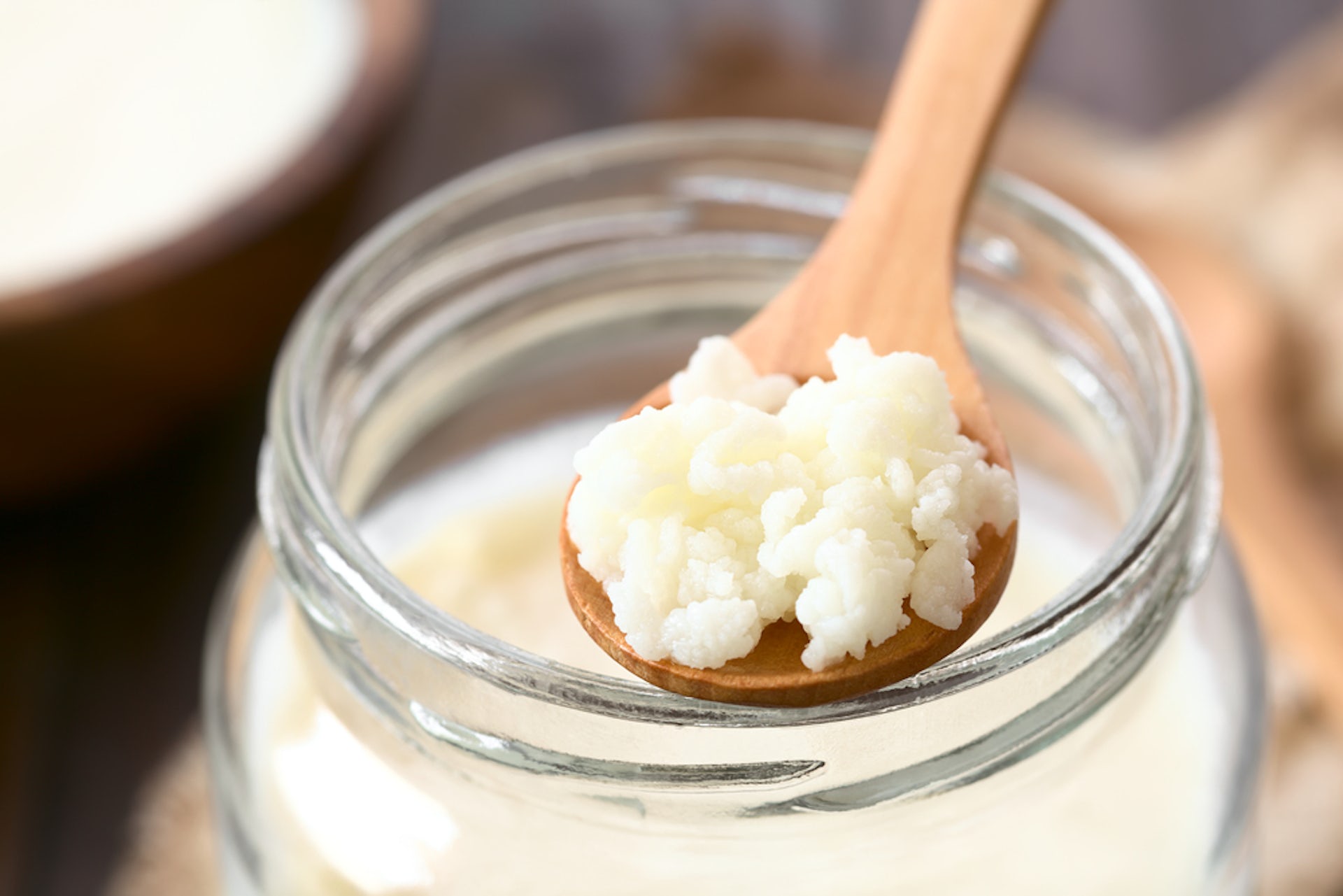 Kefir in jar, with kefir grains on wood spoon