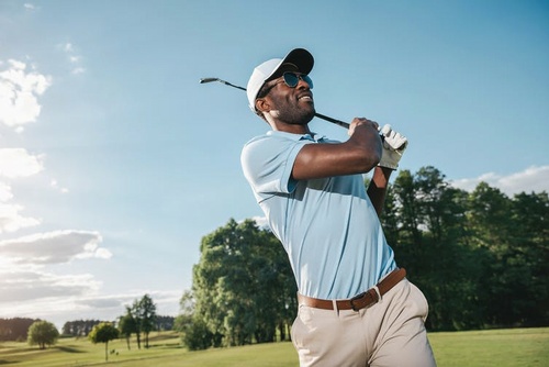 Golfer taking a shot on a beautiful course on a sunny blue-sky day.