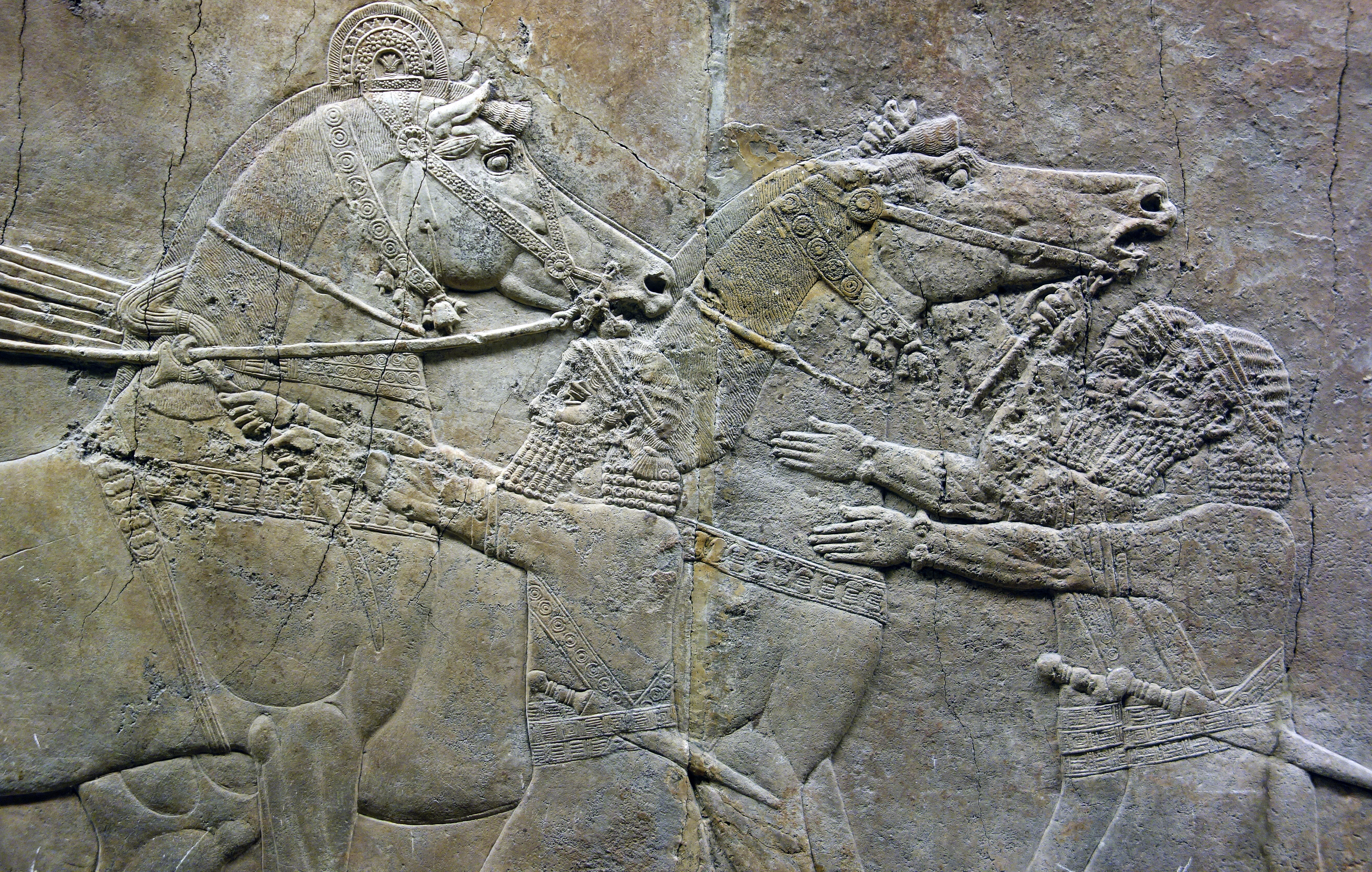 An ancient stone carving showing people with horses.