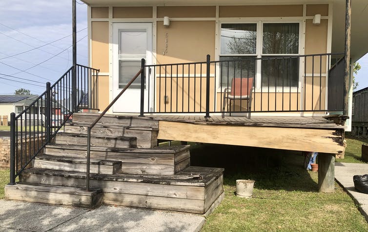 A beige house with a crumbling porch