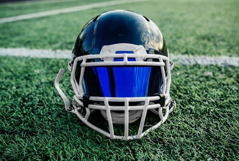 Football helmet with a visor atop a grassy football field