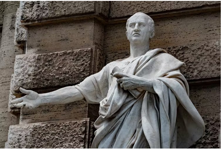 A marble statue of a Roman emperor with an arm outstretched.