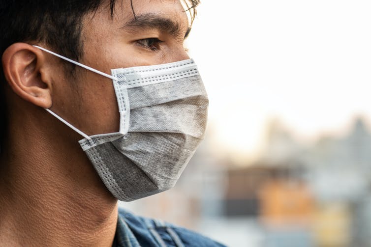 A side view of man wearing a surgical mask